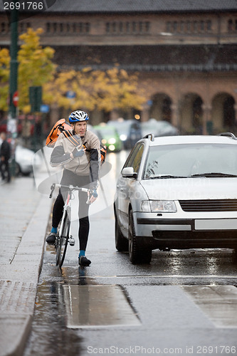 Image of Male Cyclist With Backpack Using Walkie-Talkie On Street