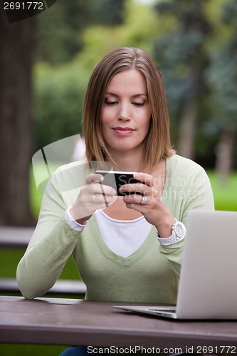 Image of Woman in Park with Mobile Phone