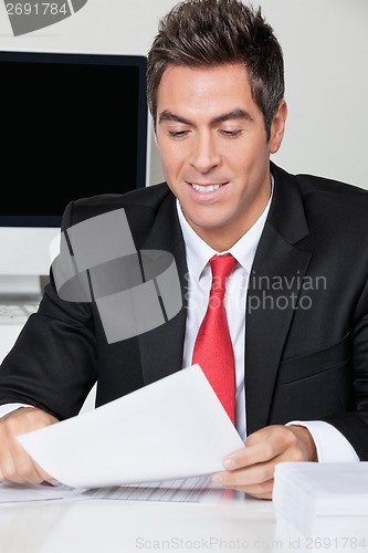 Image of Businessman Reading Document In Office