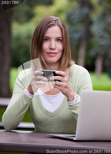 Image of Portrait of Woman in Park with Mobile Phone