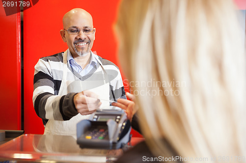 Image of Mature Man Accepting Credit Card From Young Woman At Supermarket