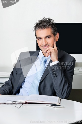 Image of Confident Businessman Sitting At Desk