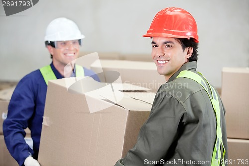 Image of Foremen Lifting Cardboard Box At Warehouse