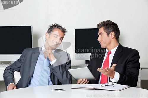 Image of Businessman Holding Digital Tablet Sitting With Colleague At Des