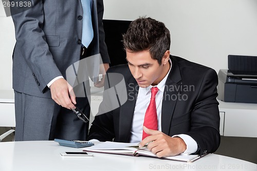 Image of Two Businessmen Calculating Finances