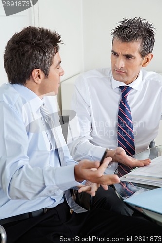 Image of Young Businessman And Colleague Discussing Paperwork