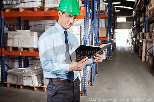 Image of Supervisor Reading Book At Warehouse