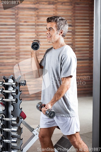 Image of Man Lifting Dumbbells In Health Center