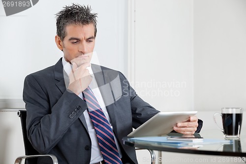 Image of Contemplative Businessman Using Digital Tablet In Office