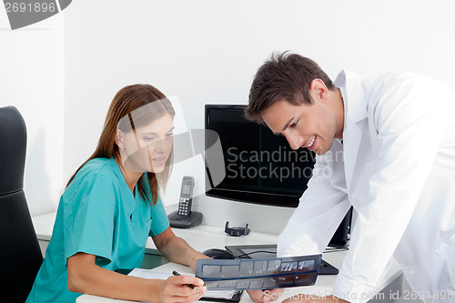 Image of Dentist With Assistant Analyzing X-Ray Report