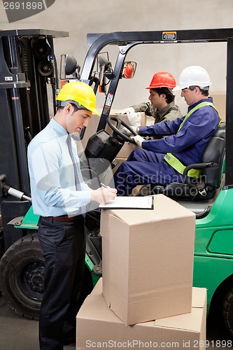 Image of Supervisor With Foremen Working At Warehouse