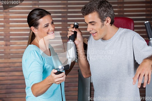 Image of Instructor Assisting Man In Getting Down From Exercise Machine