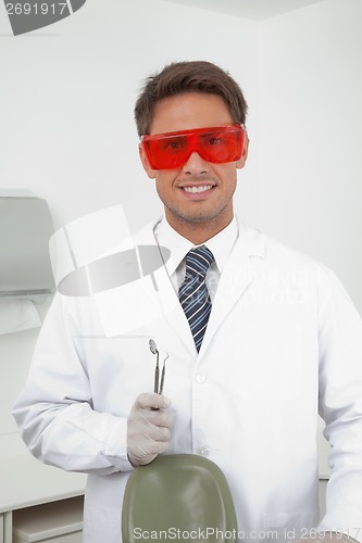 Image of Happy Dentist Holding Tools