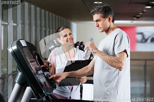 Image of Instructor Looking At Male Client On Treadmill