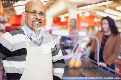 Image of Grocery Store Cashier Standing At Checkout Counter