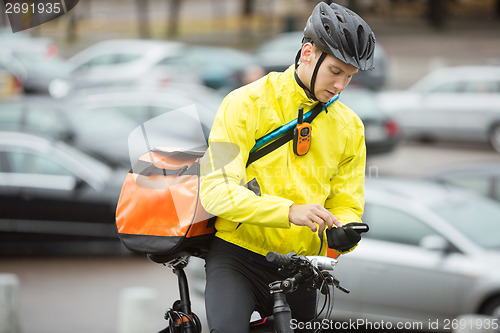 Image of Male Cyclist With Courier Bag Using Mobile Phone On Street