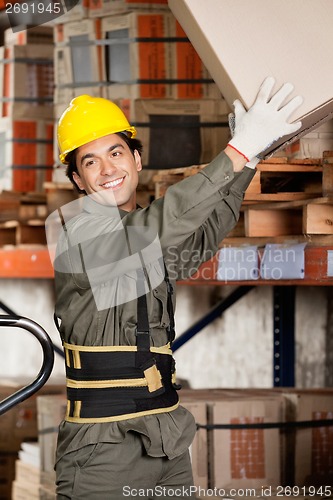 Image of Foreman Lifting Cardboard Box At Warehouse