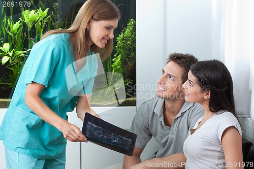Image of Dentist Showing Dental X-Ray To Couple