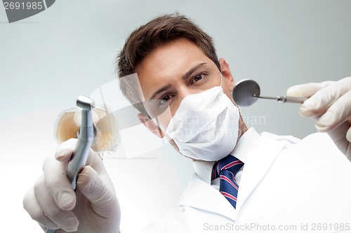 Image of Dentist Holding Angled Mirror And Drill