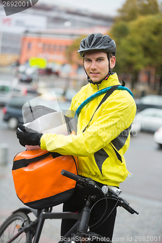 Image of Male Cyclist Putting Package In Courier Bag On Street