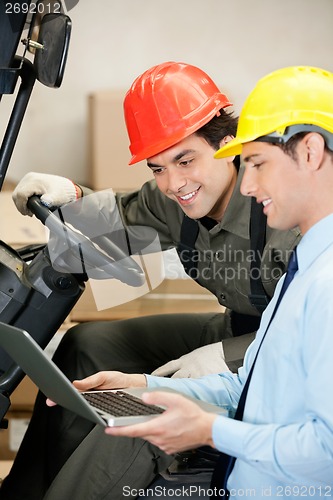 Image of Male Supervisor And Forklift Driver Using Laptop