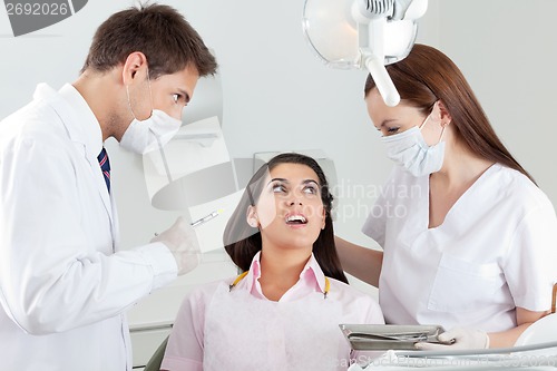 Image of Dentist Looking At Nurse Comforting Patient