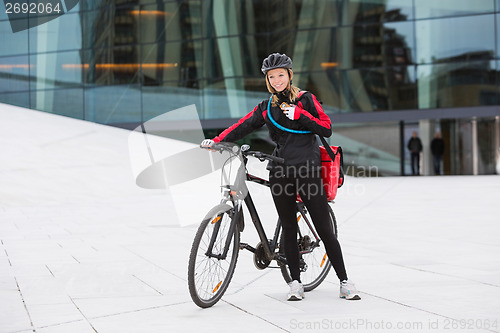 Image of Female Cyclist With Courier Delivery Bag Using Walkie-Talkie