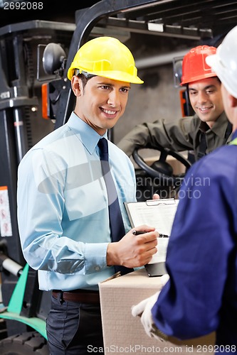 Image of Male Supervisor Showing Clipboard To Foreman