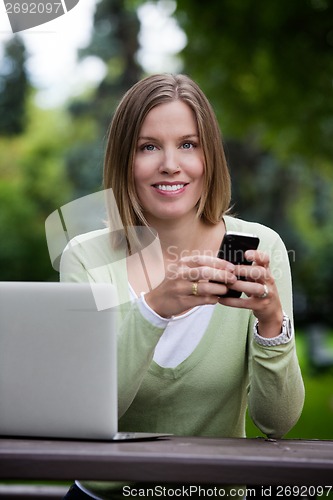 Image of Attractive Woman in Park with Smart Phone