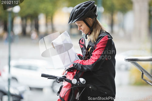 Image of Female Cyclist Putting Package In Courier Bag