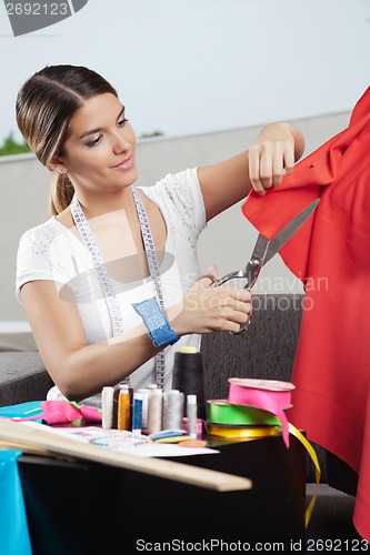 Image of Designer Cutting Red Fabric
