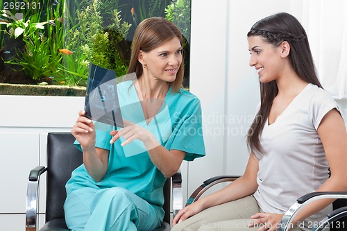 Image of Dentist Showing X-Ray Report To Woman