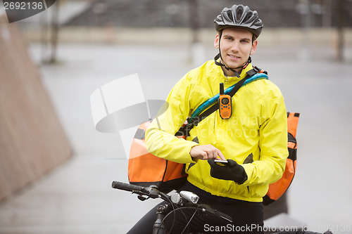 Image of Male Cyclist With Courier Bag Using Mobile Phone On Street