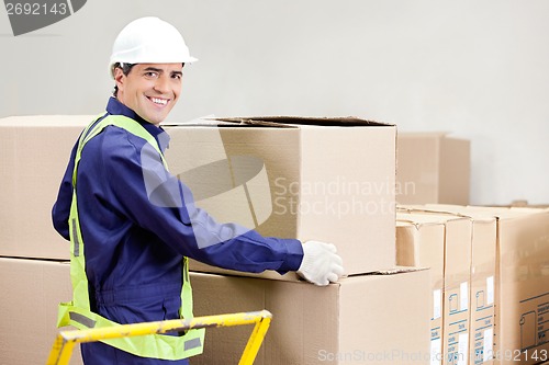Image of Foreman Holding Cardboard Box in Warehouse