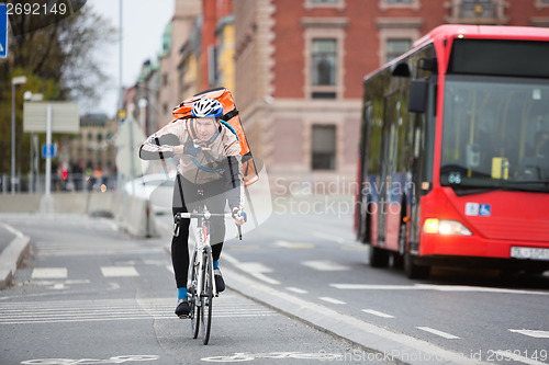 Image of Courier Delivery Man Using Walkie-Talkie While Riding Bicycle On