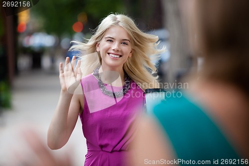 Image of Woman Waving Hello on Street