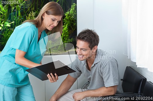 Image of Dentist Showing Something To Patient On Clipboard
