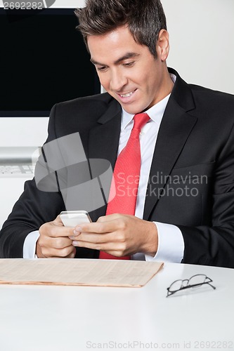 Image of Businessman Using Cell Phone At Desk