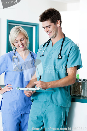 Image of Male Doctor Writing On Clipboard With Colleague At Clinic