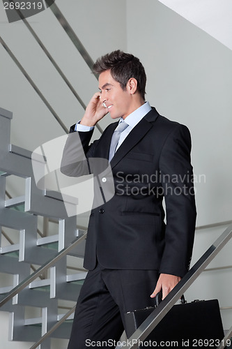 Image of Businessman On Call Walking Down The Stairs