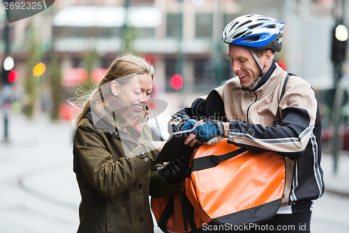 Image of Courier Delivery Man Showing Digital Tablet To Young Woman