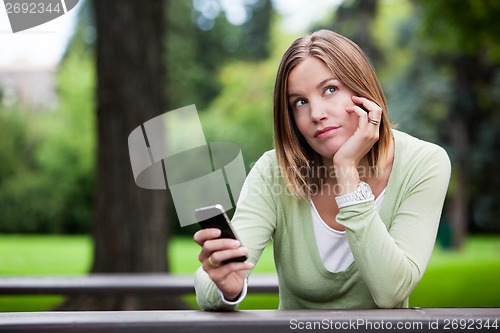 Image of Thoughtful Woman holding Cell Phone