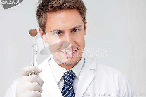 Image of Dentist Holding Angled Mirror And Carver