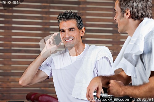 Image of Man On Call While Friend Looking At Him In Health Club