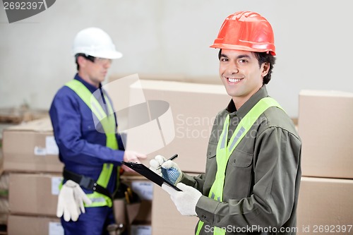 Image of Supervisor Writing Notes Clipboard While Foreman Working At Ware