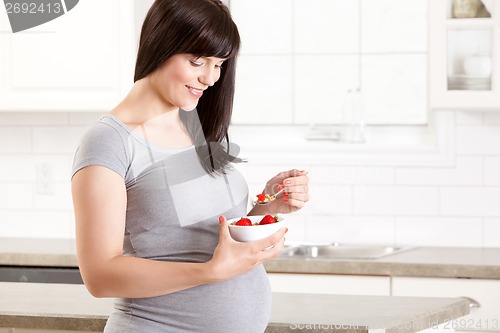 Image of Pregnant Woman in Kitchen Eating Healthy Snack