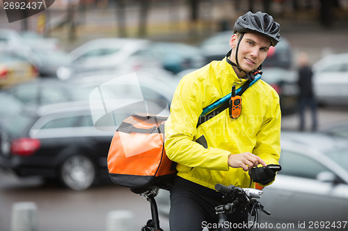 Image of Male Cyclist With Courier Bag Using Mobile Phone On Street