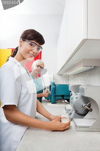 Image of Dentist Holding Dental Plaster Mold With Assistant At Clinic