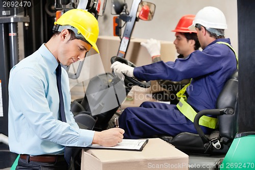 Image of Male Supervisor Writing On Clipboard At Warehouse