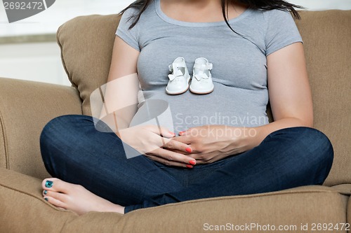 Image of Pregnant Woman With Baby Shoes On Her Belly